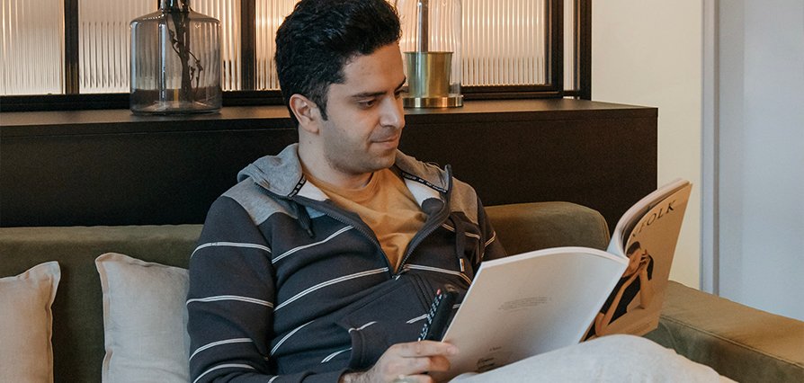 Person reading documents in a furnished living area of a business apartment