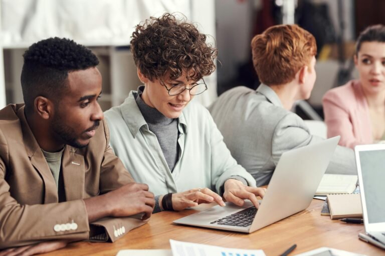 Zwei Berufstätige, die an einem Laptop in einem modernen Coworking Space zusammenarbeiten