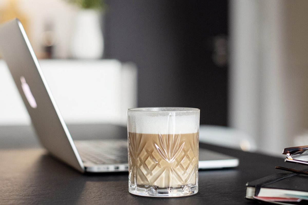 a desk in an office with an open laptop and a fresh coffee