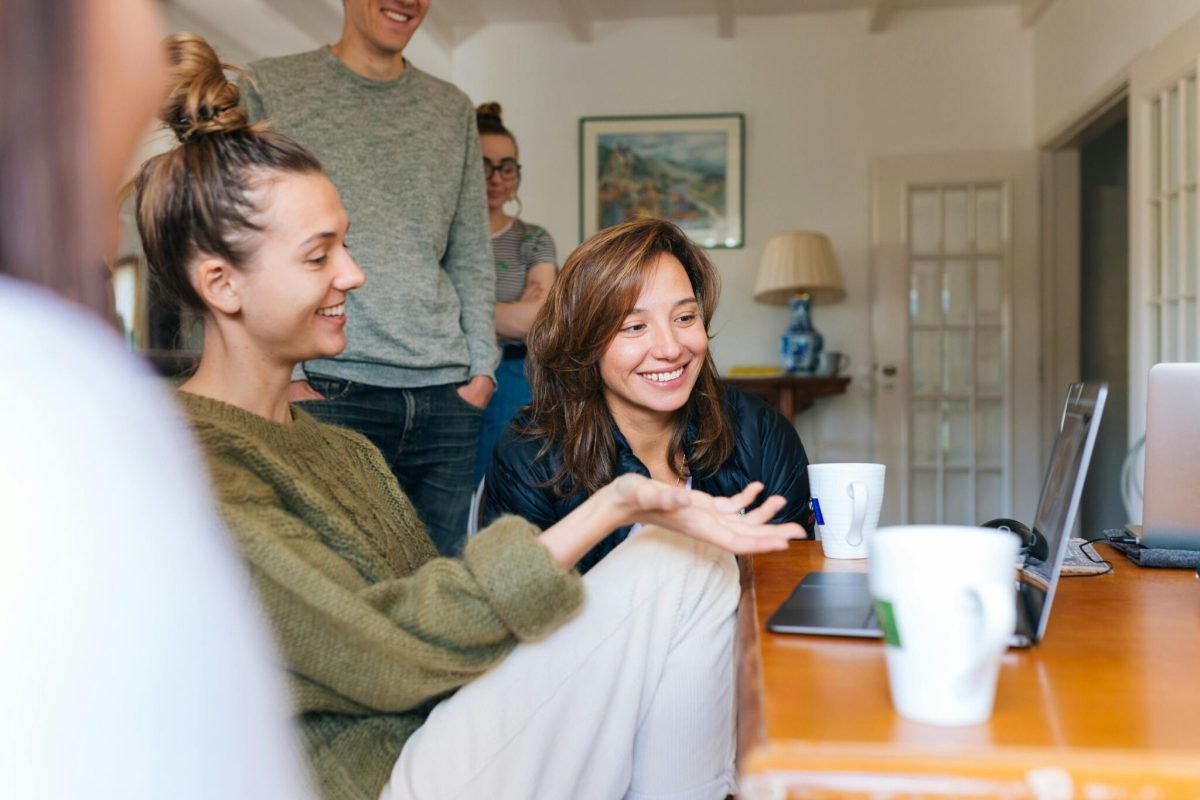 two girls sitting on the floor checking a laptop with a smile